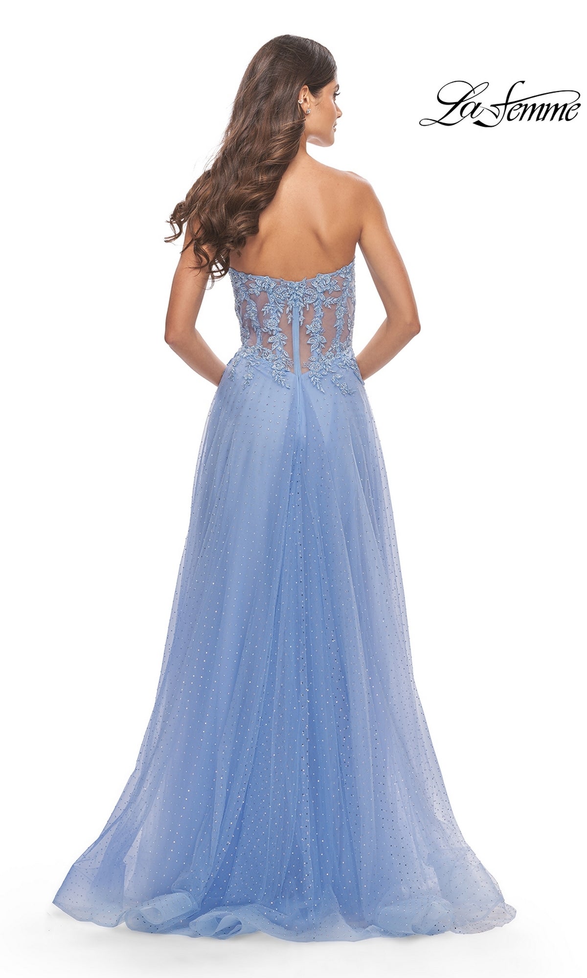 A woman wears the La Femme Strapless Sheer-Waist Prom Dress 31367 in light blue, featuring a strapless neckline, sheer lace-embroidered back, and a flowing A-line tulle skirt.